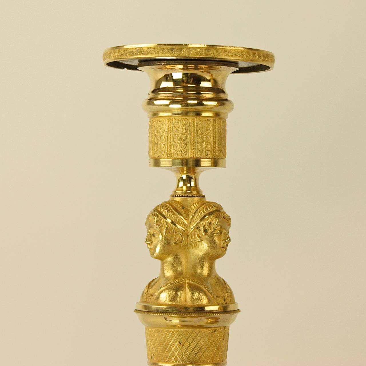 A beautiful pair of Empire candlesticks decorated with three female busts, dressed in the fashion of the time, resting on a finely chiseled and fluted shaft, supported by three pairs of flat pumps/slippers - the fashionable shoe of the gentle ladies
