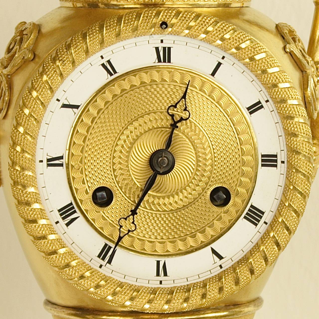 Early 19th century French Empire Ormolu Vase-Shaped Removable Lid Mantle Clock

An Empire ormolu mantle clock, the white enamel and guilloche gilt-bronze dial with Roman numerals within a urn-shaped case surmounted by two scrolled handles,