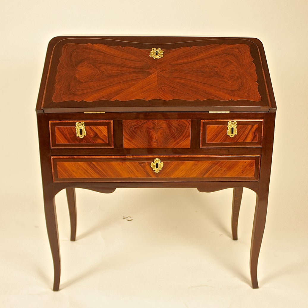 A shaped fall-front opening to reveal a leather-lined writing surface, four drawers, pigeon-holes and a secret door, with two small drawers and one full-lenght drawer above a shaped apron, on tapering cabriole legs. The piece is veneered in