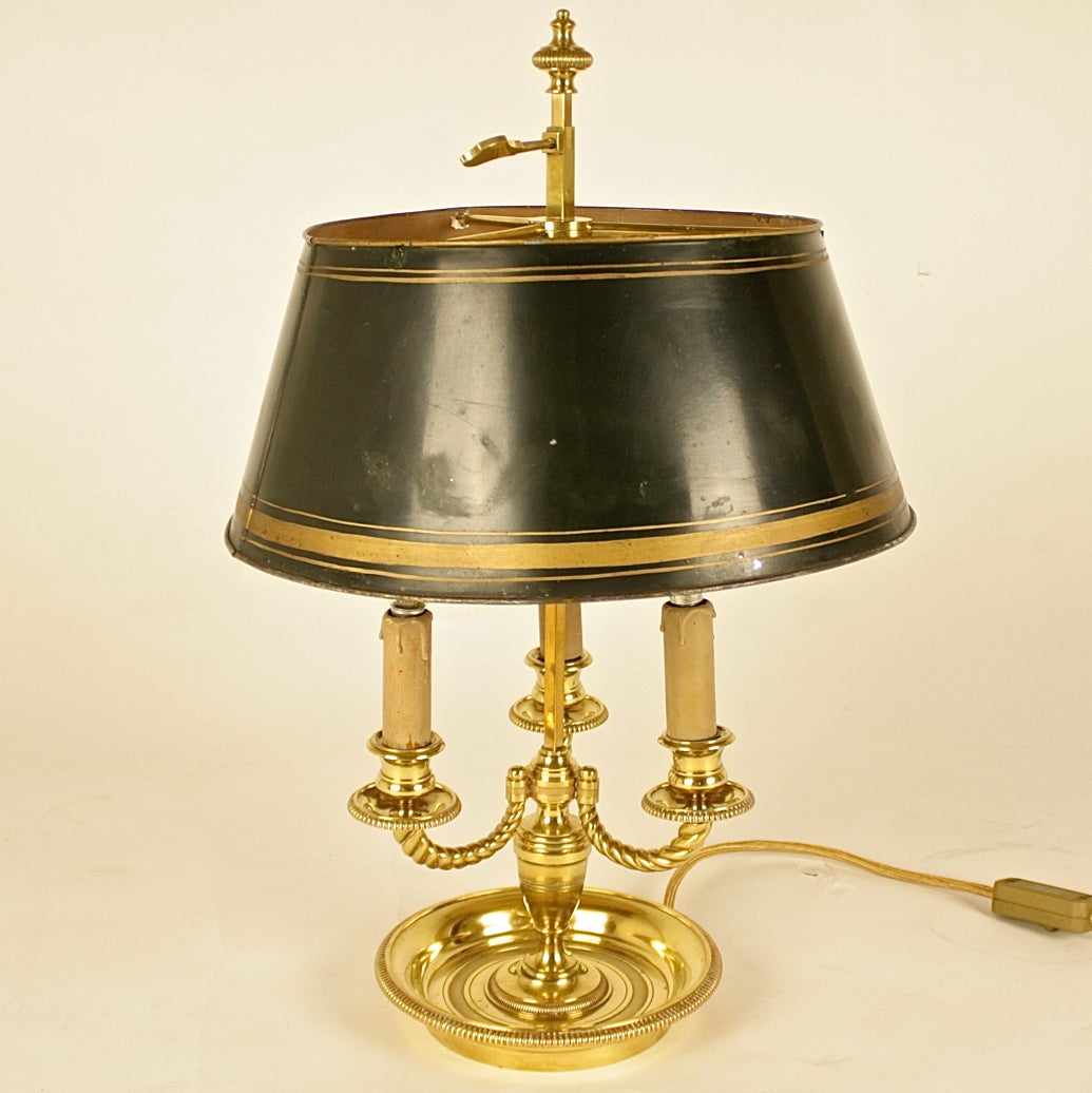 French Louis XVI style three light bouillotte lamp with an adjustable tole shade and three scrolled arms, raised on a beaded circular base. The original shade of dark green colour with bronze banding.