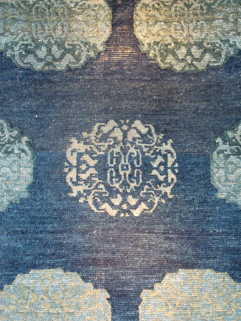 This evocative Tibetan khaden or sleeping rug, draws large stylized peonies inspired by Chinese textile design of the Ming and Ching dynasties against a transplendent indigo field. While a repeat design is used, the weaver has thoughtfully and