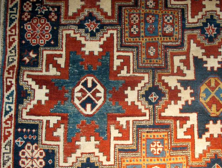 This exceptional East Caucasian rug draws large ‘Leshghi stars’ on an indigo field. The outer red and white portions of these stars alternate as do the green and blue inner stars, as well as their gold and white central octagons. Negative space is