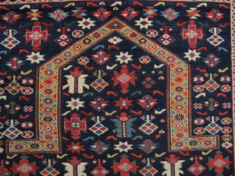Rows of alternating ‘ashik’ and palmette forms interspersed with diamonds and abstracted vegetal ornament are drawn in vivid color against the deep indigo ground of this Chichi prayer rug. Rich tones of ruby red, emerald green, rose, several blues,