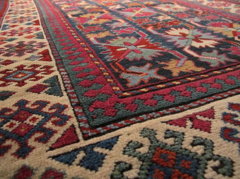 Columns of rosettes with vegetal tendrils of the type seen in the ‘harshang’ or ‘crab’ borders of Caucasian and Northwest Persian main carpets are drawn with gusto against the indigo field of this Caucasian Talish prayer rug. The spacious white