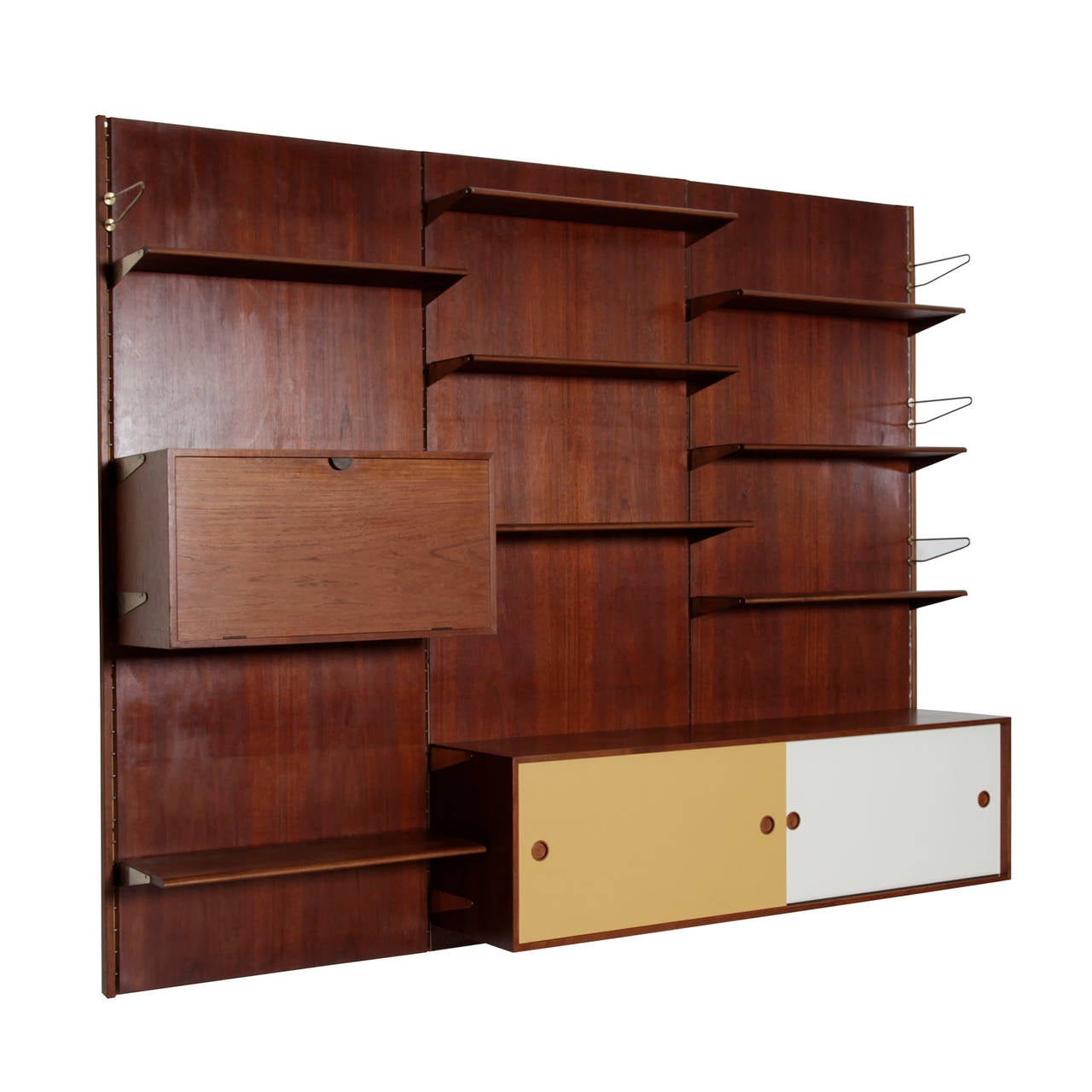A wall-mounted shelving system consisting of three teak panels with eight shelves, one cabinet with painted sliding doors, one bar cabinet and one chest of drawers, shelves and cabinets can be easily moved to any configuration. Designed by Finn Juhl