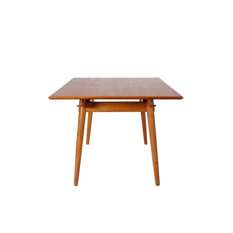 A beautifully crafted dining table with hidden leaf storage underneath the top.
Top in teak on a base of oak, steel and brass hardware. Total length with both leaves is 244 cm / 96 inches. Designe by Hans Wegner in 1953. Made by master cabinetmaker