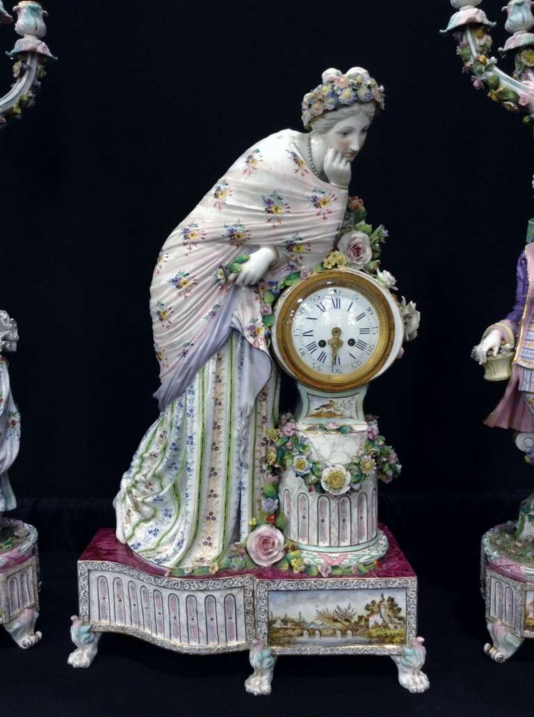 Large German polychrome porcelain mantle clock set consisting of two large  six lights candelabra, richly decorated with flowers and characters gallant and a large pendulum representing a pensive young woman sitting on the dial.
Brand Dresden blue