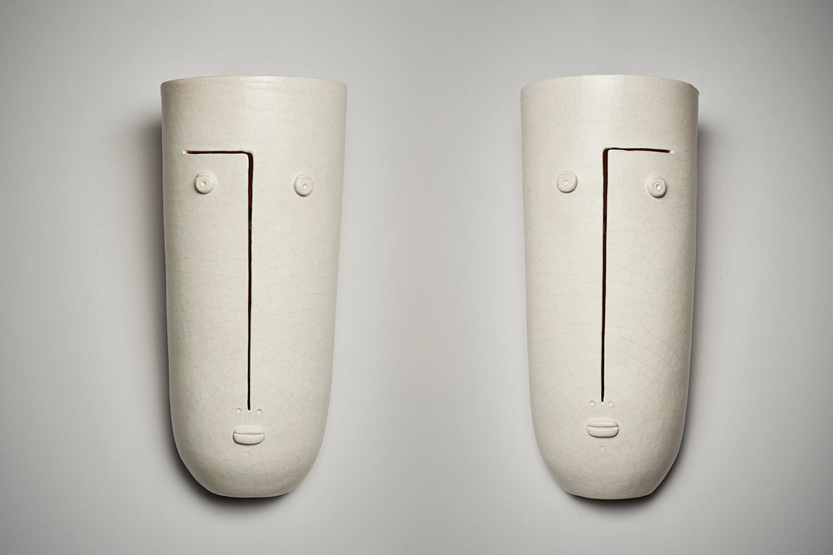 Important stoneware pair of biomorphic wall lamps , glazed in crackled and matt white, and decorated with stylized visages. 

All the Dalo's creations are unique pieces (sculpted and never molded), and signed by the french artists. 

They are