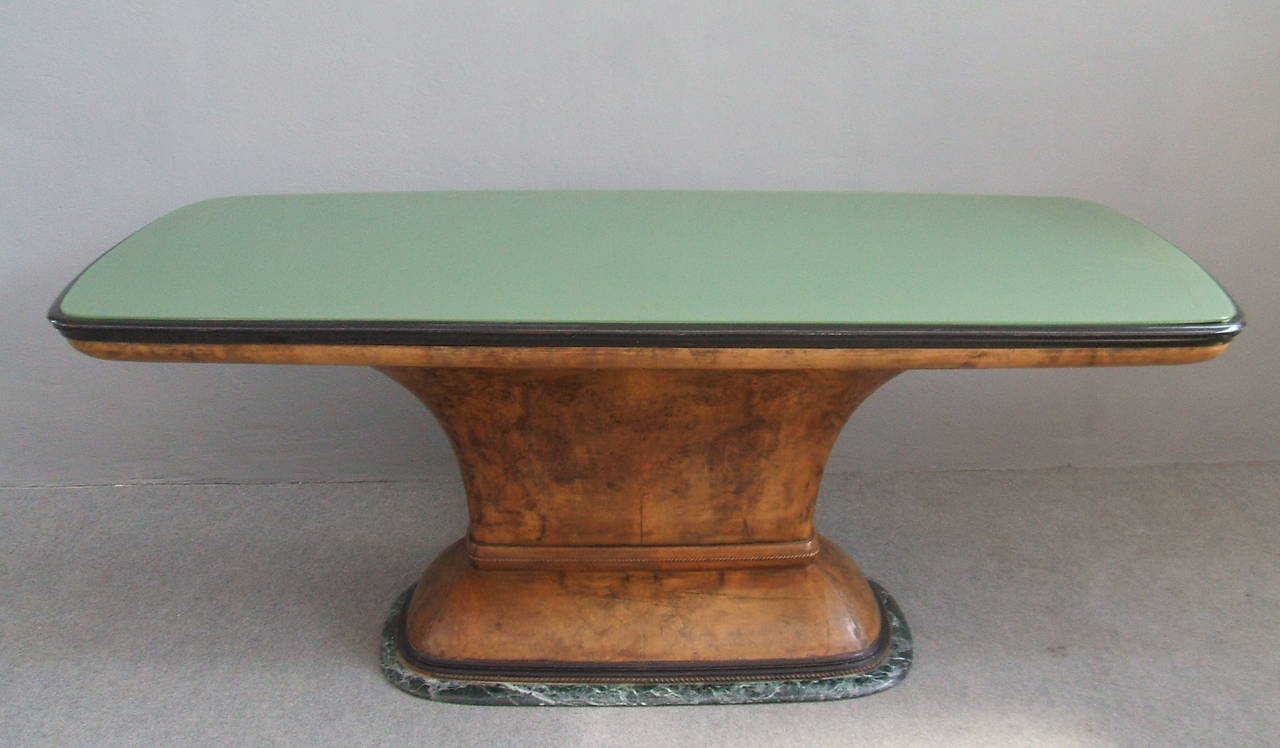 Very nice table with green glass top.
Elegant central wooden base placed on a green marble.