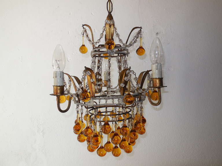 Housing 3 lights, bulb holders are in wood.  Murano drops in a dark yellow, but not quite amber.  Gold gilt metal tole with macaroni bead swags throughout.  Beading and florets on top and middle.  Adding 19