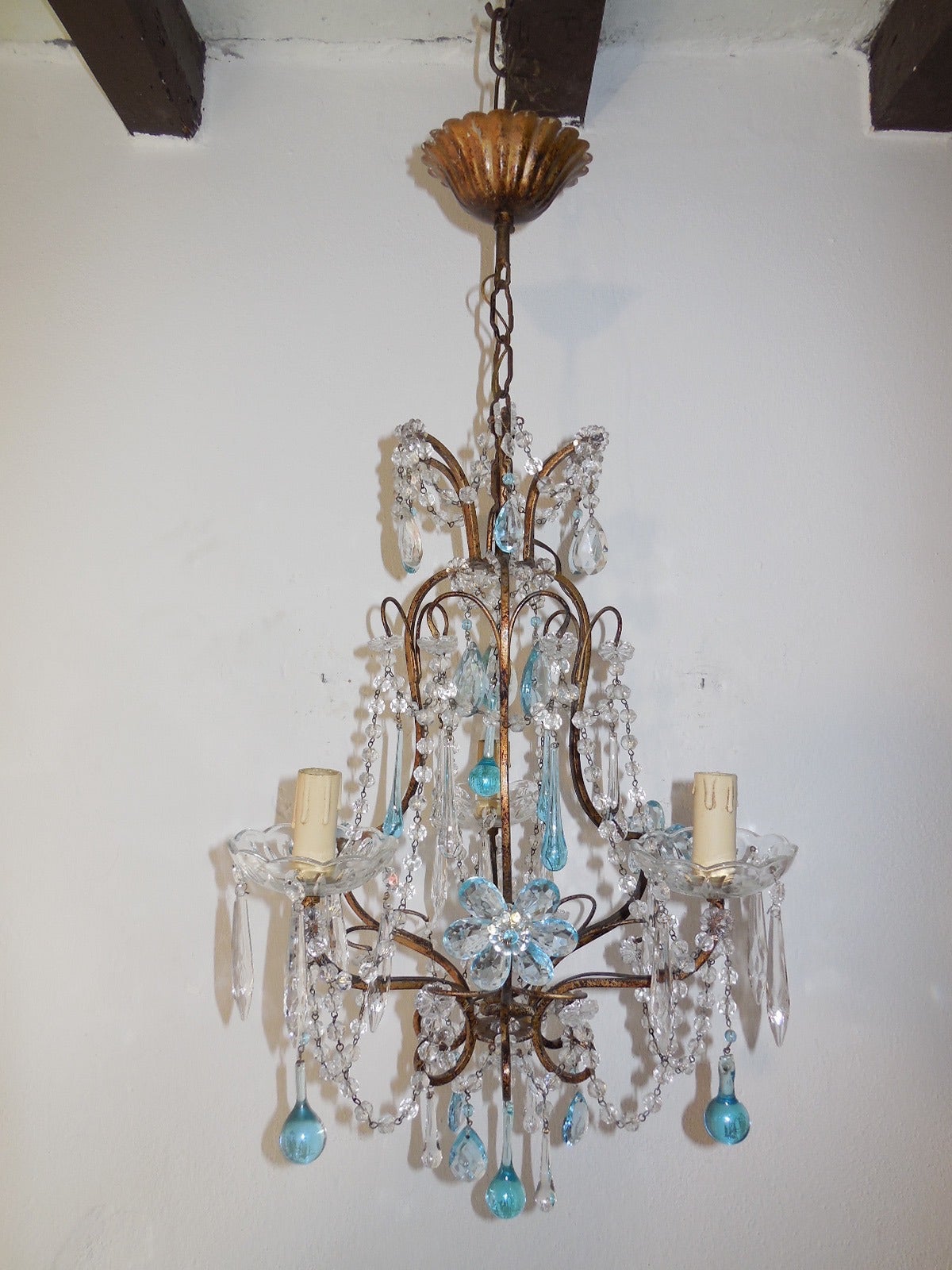 Housing 3 lights, sitting in crystal bobeches dripping with crystal spears.  Gilt metal body with swags throughout.  Adorning aqua prisms, flowers, Murano drops and beads.  Adding another 8”of original chain and canopy.  Re-wired and ready to hang. 