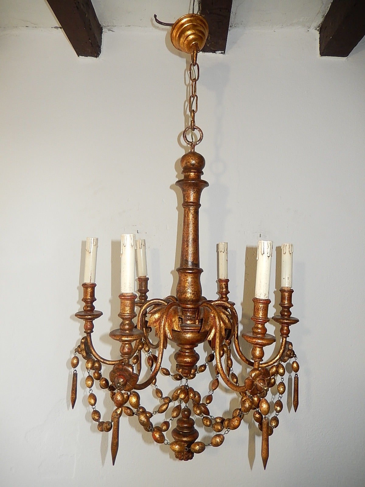 Housing six lights, gold gilt metal leaves with hand carved flowers, prisms and beads on gilt wood.  Also gilt wood tassel as finial.  Adding another 9 inches of original chain and canopy.  Re-wired and ready to hang.  Free priority shipping from