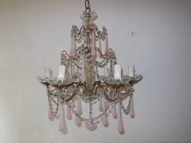 Housing six lights, bulb holders sitting in crystal bobeches. Murano glass center. Gold gilt body with perfect patina. Swags and swags of macaroni beads, not missing one.  Crystal bobeche on top and bottom. Also adorning 24 cotton candy pink opaline