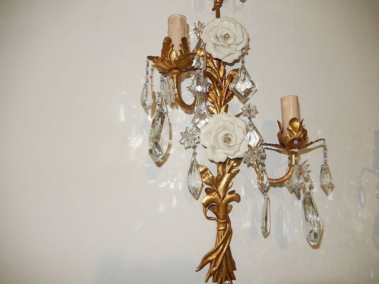 Housing 2 lights each. Gilt tole with perfect patina. French crystal stars and prisms throughout. Adorning 2 big white handmade porcelain roses on each. Re-wired and ready to hang. Free priority shipping from Italy.