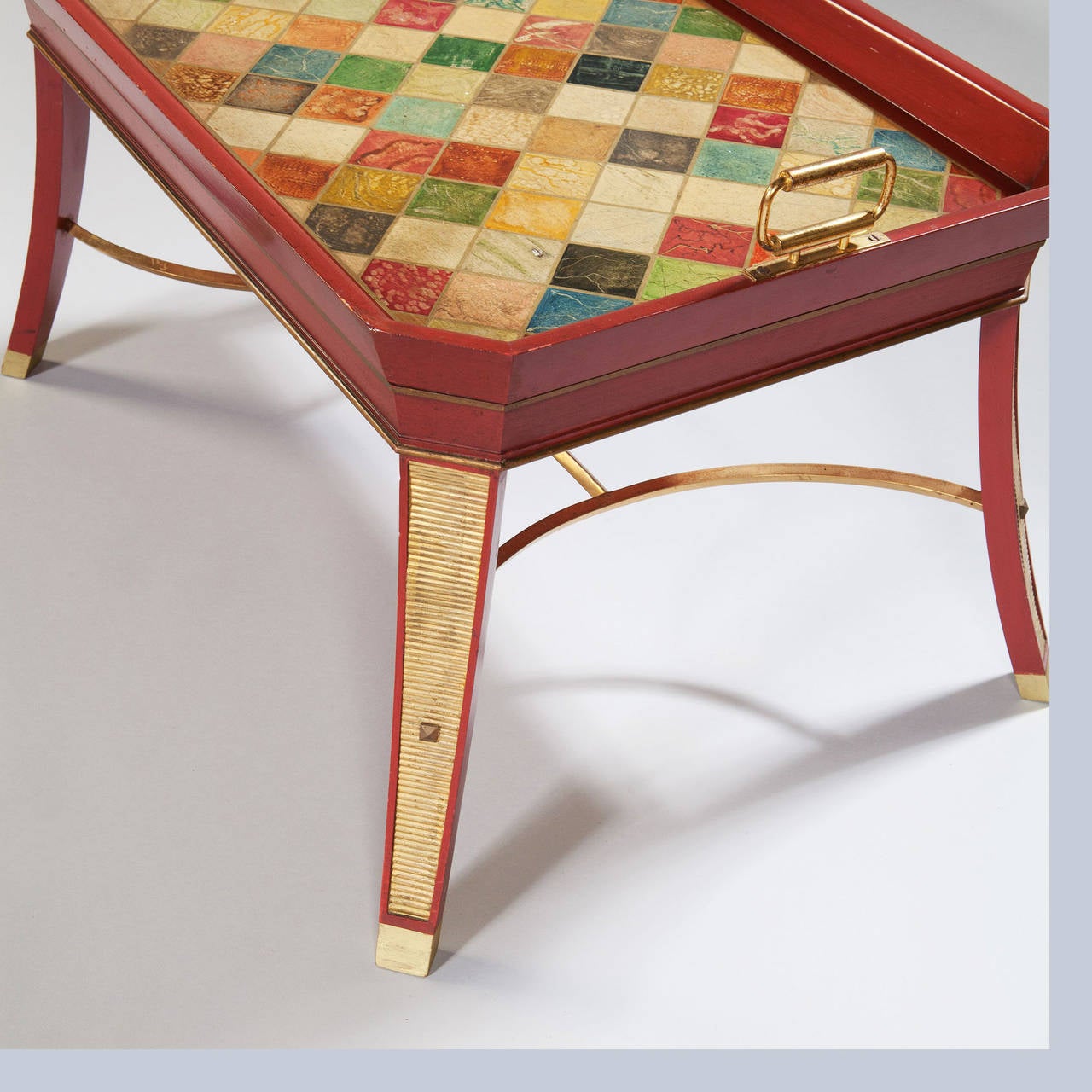 A pair of mid-20th century tray tables in the Regency Style, painted sealing wax red, the tops with faux specimen marble surface decoration and brass carrying handles and raised upon sabre legs with brass wash board mounts and linked by concave