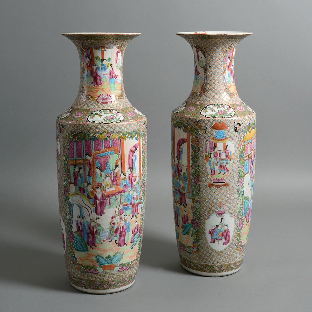 A large pair of famille rose Canton vases, of baluster form with trumpet shaped rims, the bodies decorated with panels depicting courtiers upon foliate grounds. 

Canton porcelain is a term given to Chinese ceramics produced for export to Europe