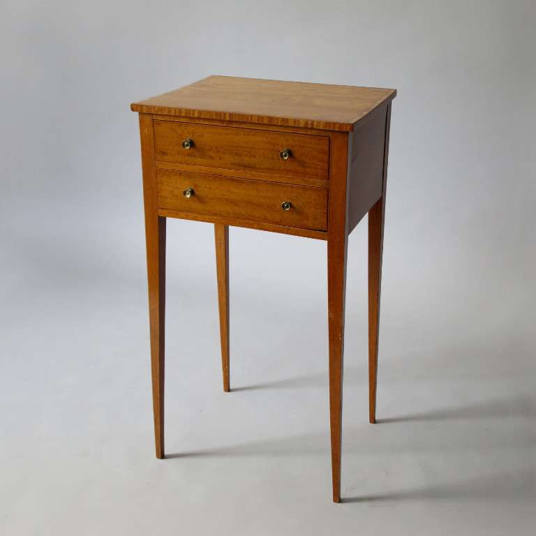 A George III Period satinwood end table in the Sheraton taste having a crossbanded top above two drawers and raised on square tapering legs. 

Non-continental