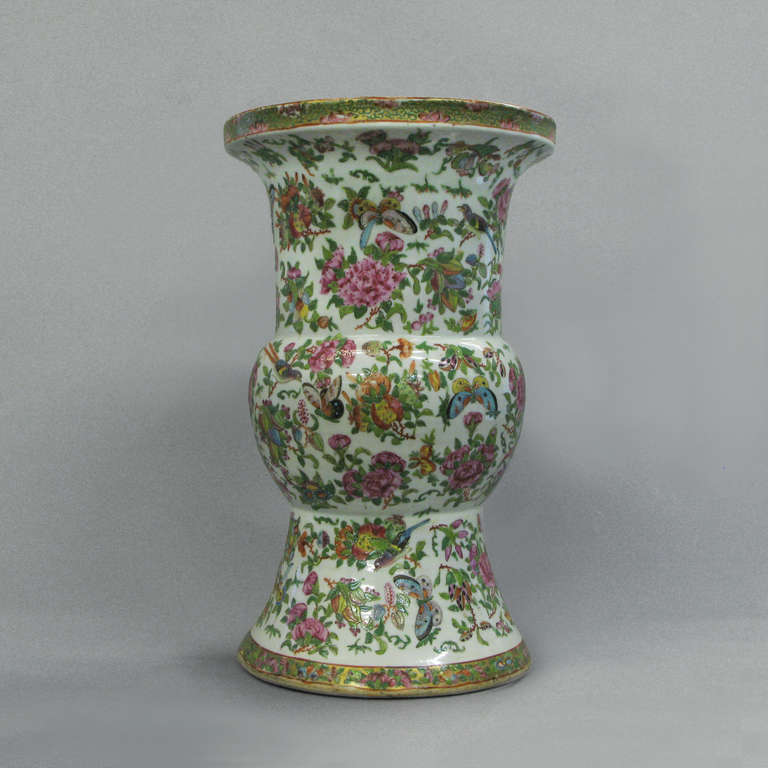 A large scale famille rose beaker vase decorated throughout woth birds, butterflies, flowers and foliage upon a white ground with gilded highlights.