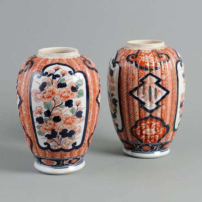 A pair of Imari vases, the ribbed bodies decorated in the traditional manner with blue, red and green glazes, articulated with floral cartouches.