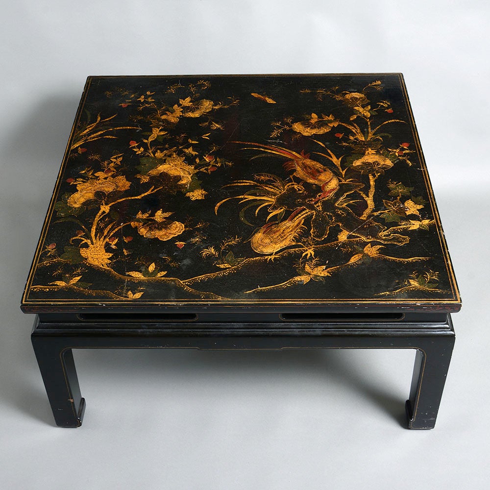 An early 20th century black and gold lacquer panel, decorated with exotic birds and set upon a shaped ebonised stand with shaped legs.