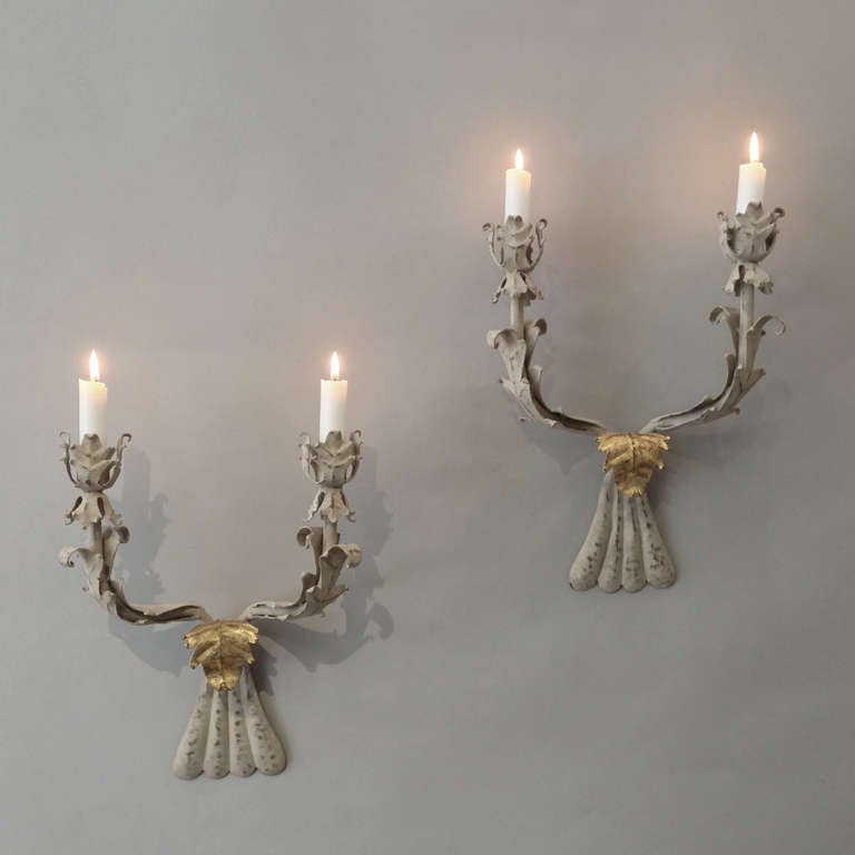 A pair of two-arm tole wall lights, of foliate form having single gilded stylized acanthus leaves.