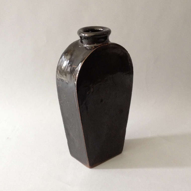 A nineteenth century black glazed pottery bottle of faceted form with ring neck.