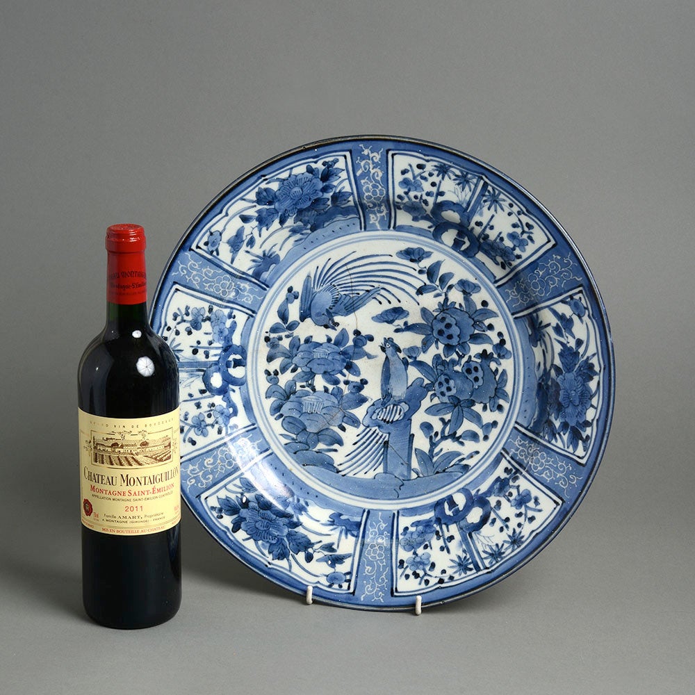 A blue and white porcelain kraak ware charger, the rim with panelled decorated, the centre painted with stylised birds and foliage. 

Hairline crack to central section.