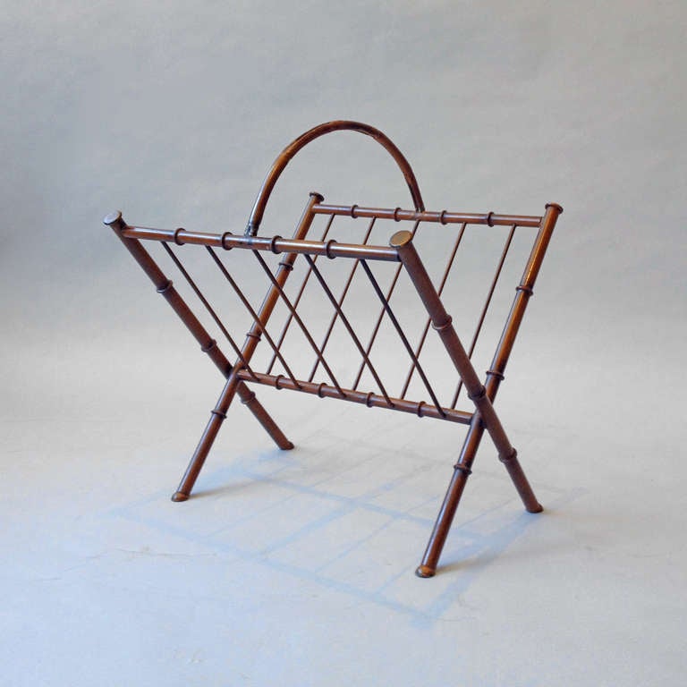 A mid-century faux bamboo cast iron magazine rack, the painted frame in imitation of bamboo shoots, having a looped carrying handle