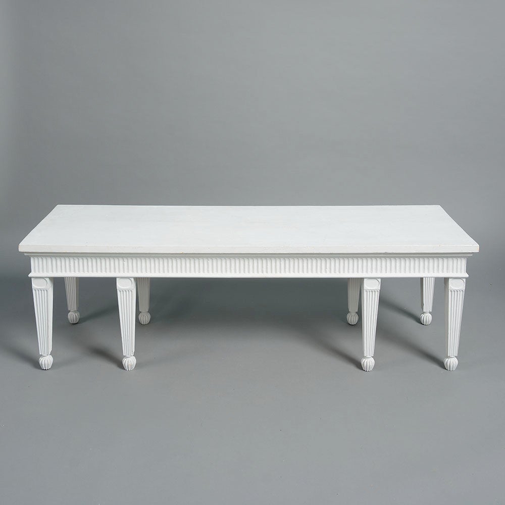 A good 20th century copy of a neoclassical hall bench in the manner of Robert Adam, of rectangular form, the overhanging top supported on eight cluster column legs, of square tapering form with carved fluted decoration. 

This hall seat relates