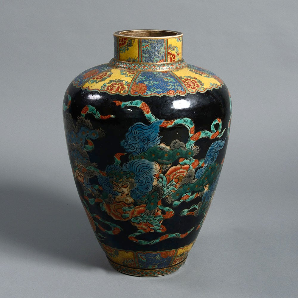 A late 19th century Arita vase of large scale, the collar and foot decorated with kimono patterns, the main body with dragons and mythical beasts in polychrome glazes upon a black ground. 

This vase was made shortly after the Japanese reopened