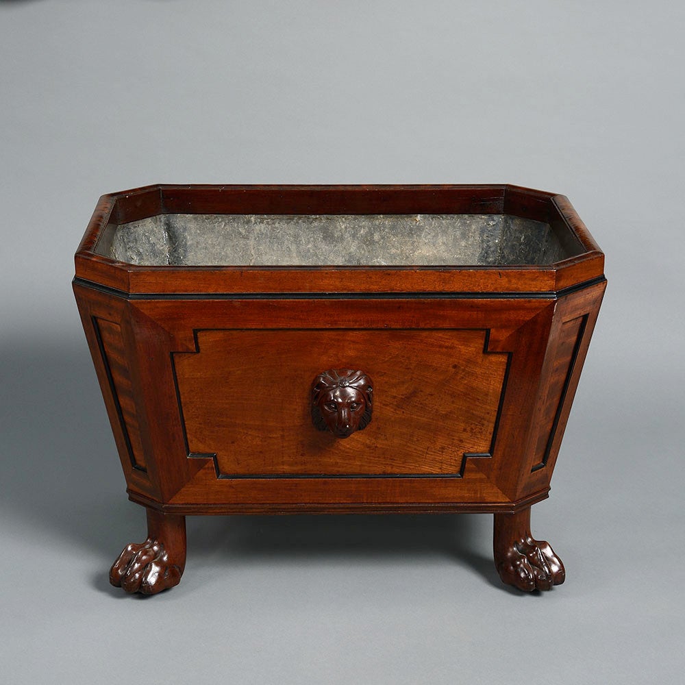 A fine early 19th century mahogany and ebonised wine cooler in the Classical taste, of sarcophagus form, retaining the original liner, the front with a carved lion mask in the manner of Thomas Hope, the sides with gilt brass handles, all raised upon