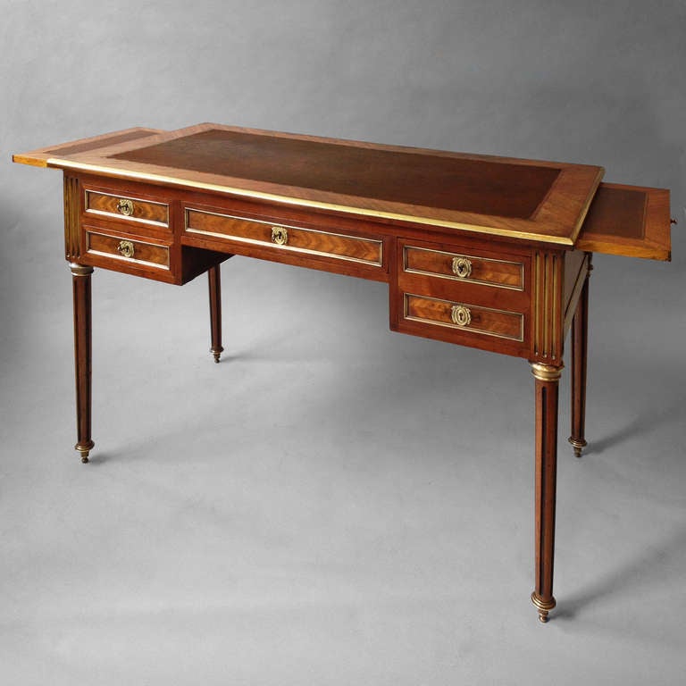 A late 19th century mahogany bureau plat in the late 18th century manner, the top with tooled dark brown leather above brass mounted drawers, the sides with leather topped brushing slides, all set upon turned fluted legs on brass sabots.