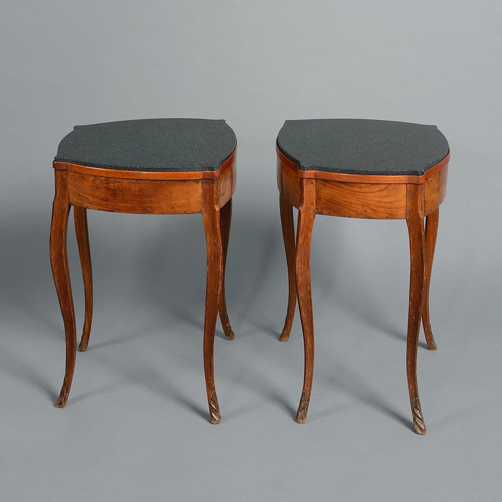 A charming 18th century pair of walnut bedside tables, of tapering form and raised upon elongated cabriole legs with carved feet, inset with later black granite tops.