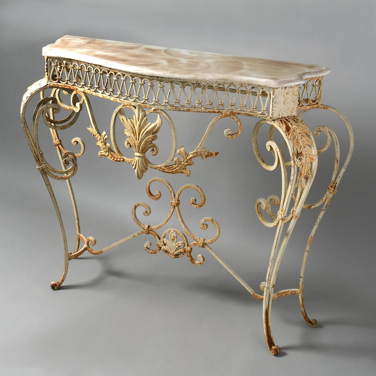 A mid-century cat iron console table in the rococo manner, the scrolling frame with pressed metal foliage and set with a serpentine white marble top