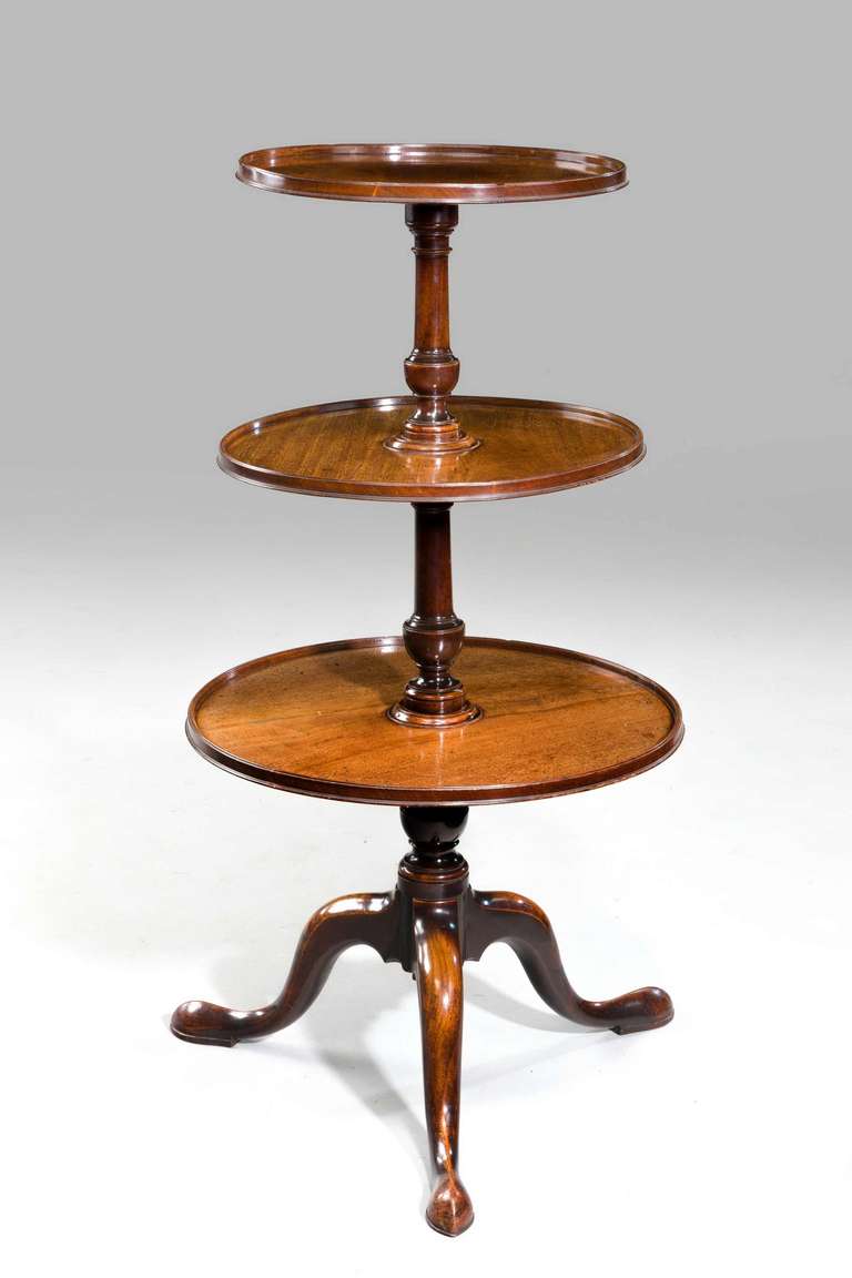 A George III period mahogany three tier dumb waiter, the baluster turned support holding three dished trays. Cabriole legs terminating in pad feet. The whole a very good color and patina.

