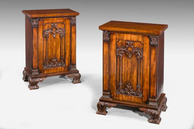 Pair of Regency period mahogany pedestal cupboards with column uprights and well carved decoration to the inset panels of the doors. Elaborate carved ogee feet.