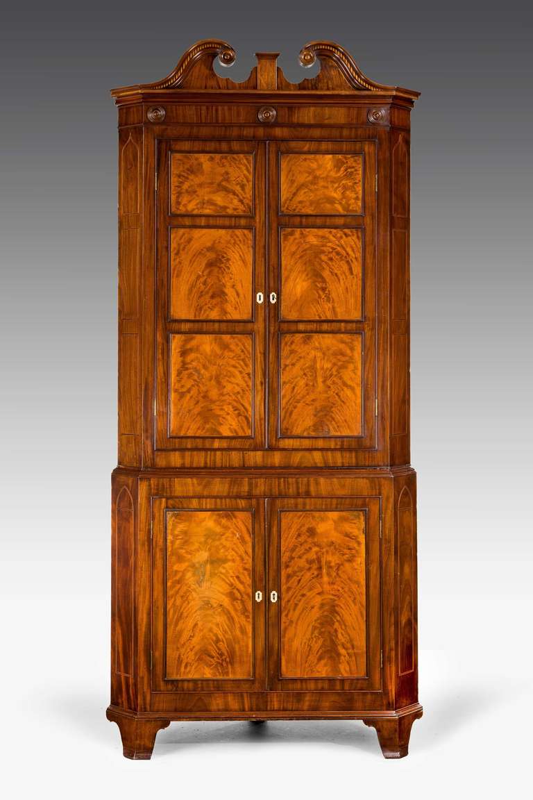 A highly figured George III period mahogany double corner cupboard, the inset panels leaf matched within an 