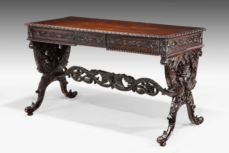 A fine Indian library table, beautifully carved on lyre shaped ends terminating in scroll supports, the elaborate cross stretcher pierced.

RR.