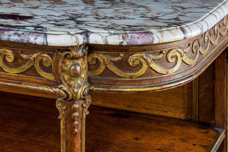 An oak and parcel-gilt side cabinet, the top border of vitruvian scrolls, supports with reeded and applied decoration terminating in French scroll feet. The gilding original now somewhat tired.

