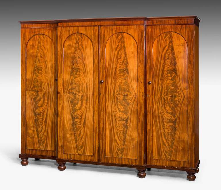 An exceptional finely figured mid-19th century mahogany breakfront Wardrobe, the centre section retaining four original sliding trays and fitted drawers with swan neck handles.