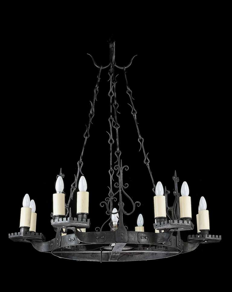 A twelve-arm, cast iron chandelier of Tudor design, the finish of patinated gun-metal shading with good cast sections and original hanging chain.

The earliest candle chandeliers were used by the wealthy in medieval times. They were generally