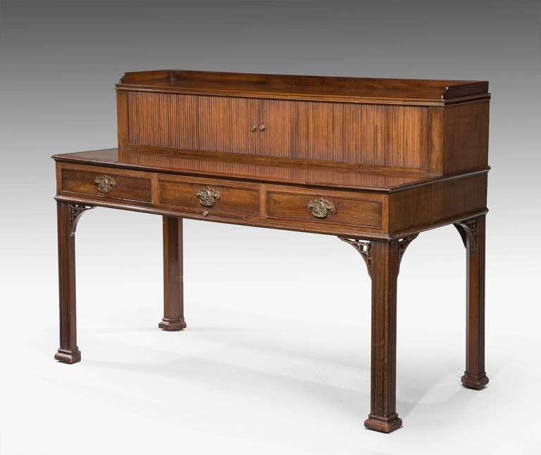 George III period writing table of unusual form, the central section sliding forward to reveal a writing slide, tambour upper section with three fitted drawers and pigeon holes, replacement brass handles of exceptional quality, standing on chamfered