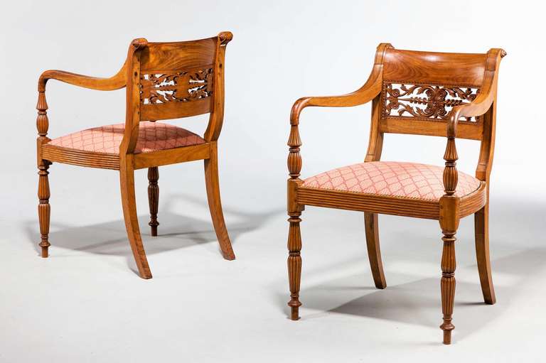 A fine set of four Regency period Anglo-Indian teak elbow chairs, the finely carved back sections with elaborate scrolls and foliage on well-turned tapering supports.
