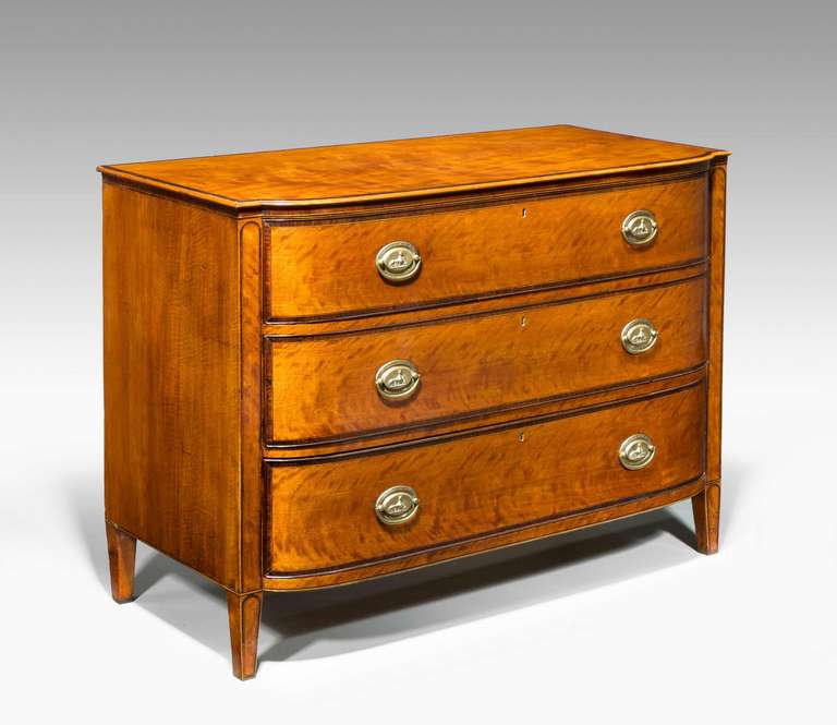 A George III period bow and break front satinwood chest of drawers with rosewood crossbanding and ebony line inlay, the oval handles incorporating sphinx surround by a Greek key pattern, the tapering supports with rosewood banding.