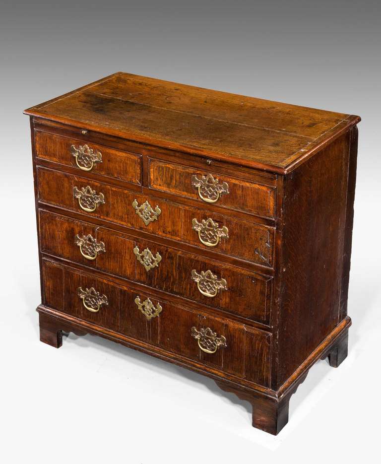 A George III period oak chest of drawers with crossbanded edges to the top and the drawers, incorporating a slide.

RR.