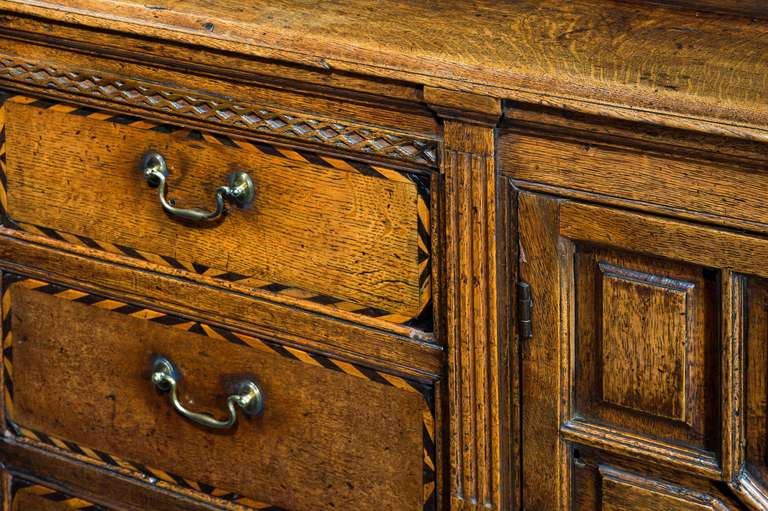 A good and sophisticated design this George III dresser base of unusually slim proportions back to front, the doors with shapely fielded panels,a block of three drawers to the centre with attractive ebony and boxwood half chevron inlay. Paneled