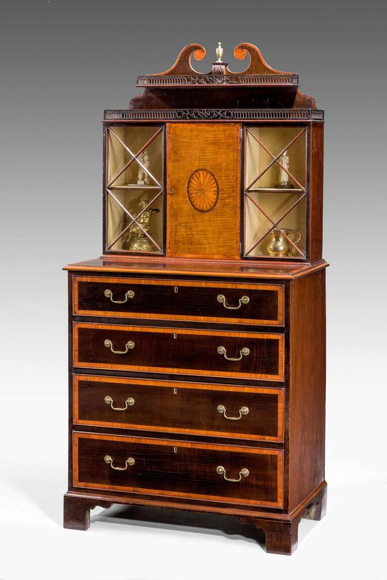A rare pair of George III period mahogany pier cabinets with display section tops and finely pierced galleries to the upper shelves, the central door of hare wood with an oval satinwood central sunburst, four drawers to the main section cross banded