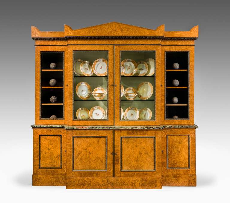 George Bullock. An excellent oak and burr oak breakfront bookcase the timbers finely figured, the waist molding with the original verte d'antico marble. The hipped pediment with stylised anthemion leaves and scrolls. The moldings of fine cast and