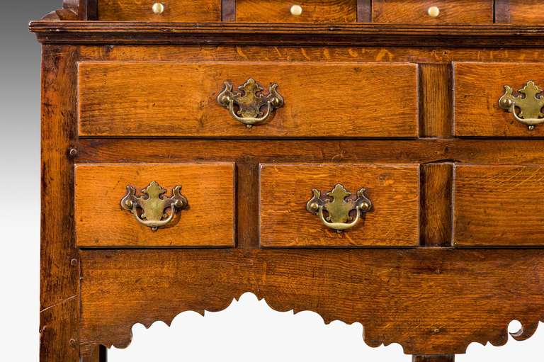 A good 18th century period dresser and rack, with nine drawers over a boarded base, the top shaped rack original to the base with pegged construction throughout with seven small spice drawers to the upper section and period cup hooks at the top of