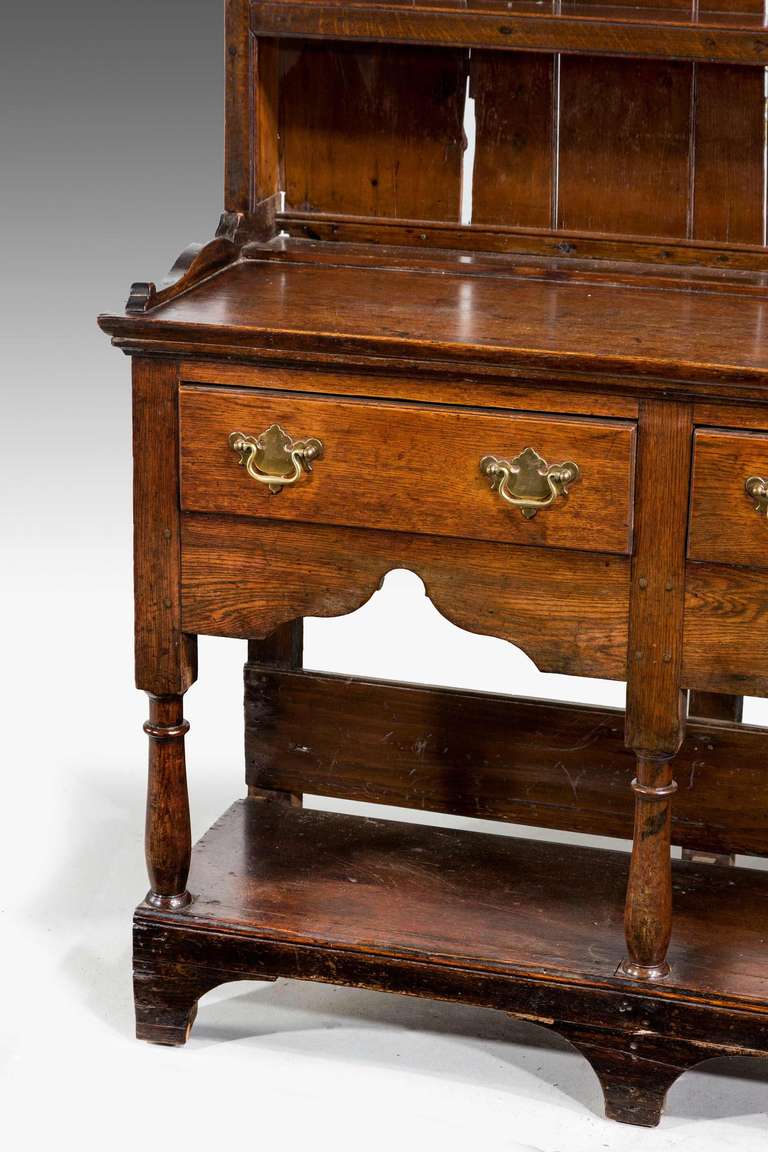 A pretty small 18th century Oak Dresser and Rack standing on a pot base with arch bracket feet and turnings, supporting three drawers above shaped freezes, the original top section with four shelves. 

A Welsh Dresser sometimes known as a kitchen